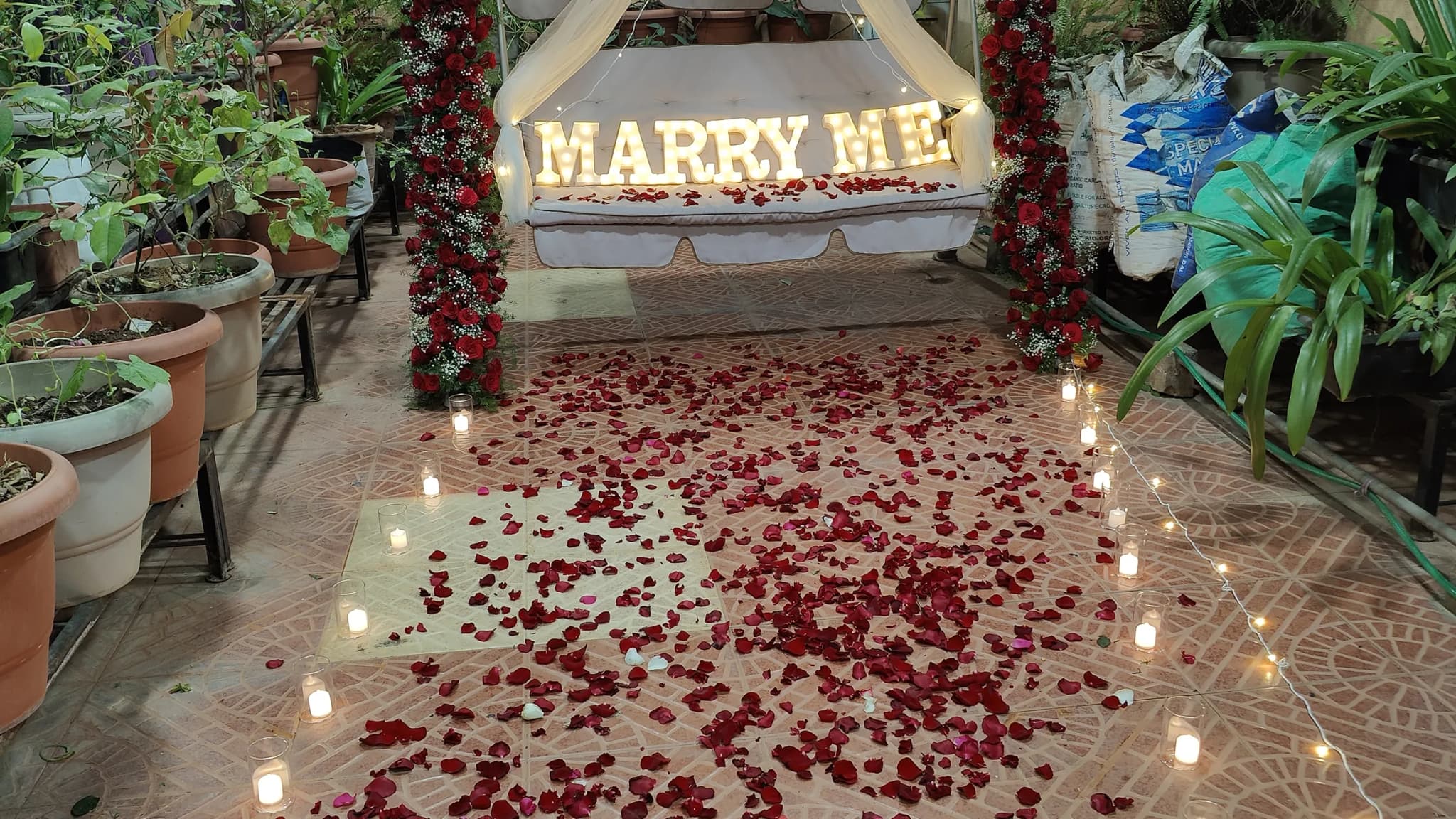 A proposal setup by We Decor in Bangalore — rose petals, candles and a floral swing